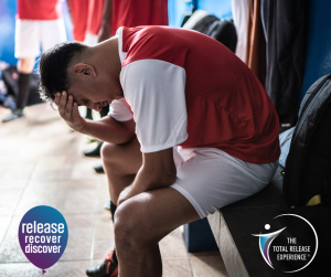 A high-level athlete sitting alone in a locker room reflecting on stress and mental health